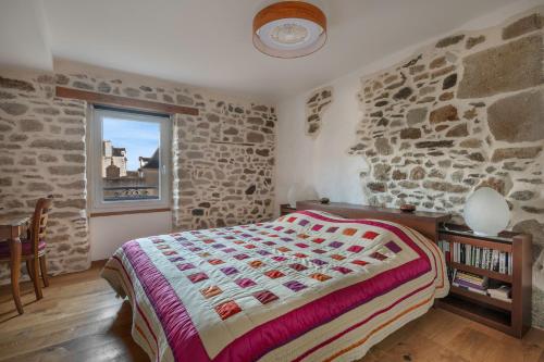 une chambre avec un lit et un mur en pierre dans l'établissement Sur le Port du Croisic - Appartement pour 4, au Croisic