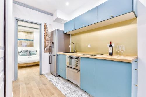 une cuisine avec des armoires bleues et un évier dans l'établissement Joli appartement au coeur du quartier Bastille, à Paris