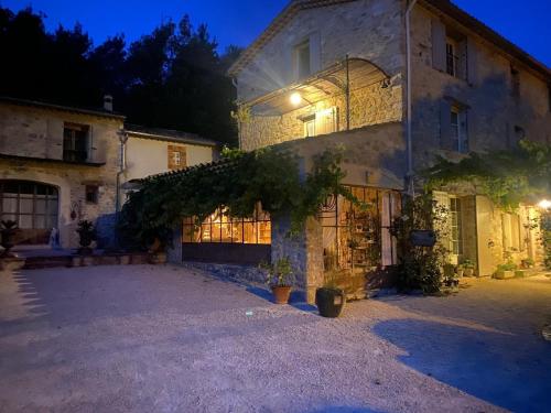 une grande maison en pierre avec une allée en face de celle-ci dans l'établissement Mas en Baronnies Provençales, à Eygaliers