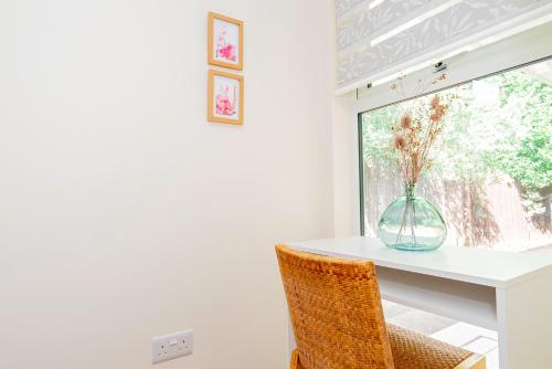 a dining room table with a vase of flowers in a window at Modern 3-Bedroom 2-Bathroom Flat with Garden at Hanwell in Greenford