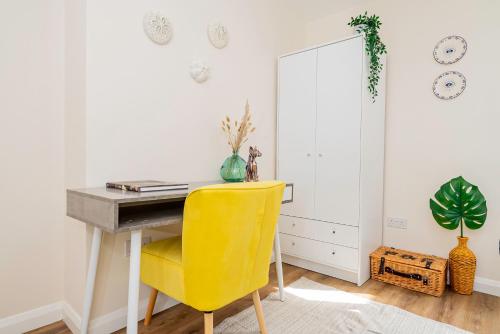 a desk with a yellow chair in a room at Modern 3-Bedroom 2-Bathroom Flat with Garden at Hanwell in Greenford
