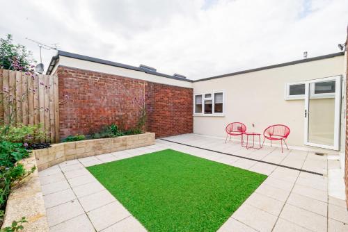 a garden with red chairs and a brick wall at Modern 3-Bedroom 2-Bathroom Flat with Garden at Hanwell in Greenford