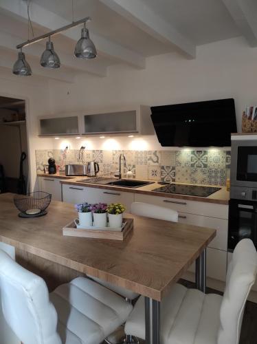 - une cuisine avec une table en bois et des chaises blanches dans l'établissement La Conquête, charmante maison de caractère, à Conques-sur-Orbiel