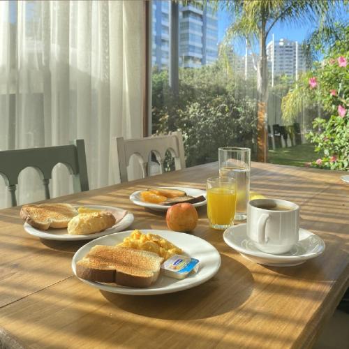 a wooden table with plates of breakfast food on it at Hotel Ajax in Punta del Este