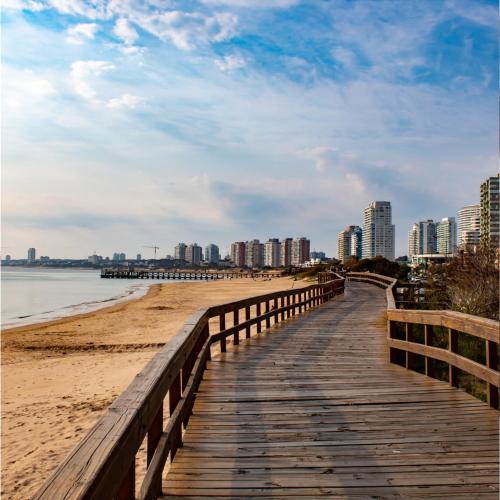 a wooden boardwalk leading to a beach with buildings at Hotel Ajax in Punta del Este