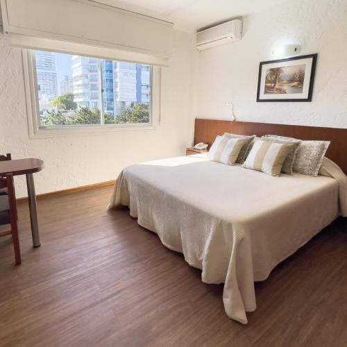 a bedroom with a large white bed with a window at Hotel Ajax in Punta del Este