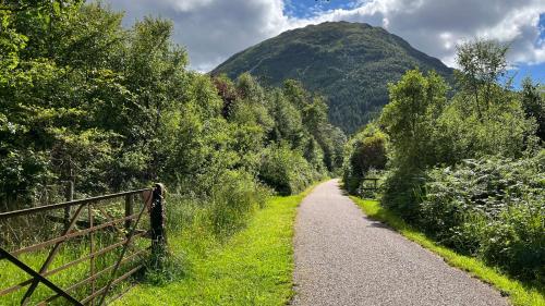 a gravel path with a mountain in the background at The Heronry Hideaway with luxury hot tub in Ballachulish