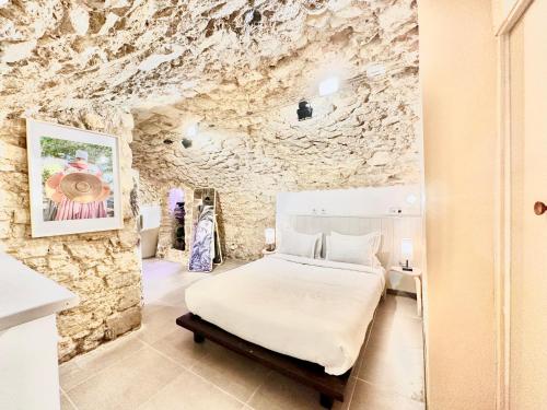 une chambre avec un lit et un mur en pierre dans l'établissement Èrsextius, NP, Aix-en-Provence, à Aix-en-Provence