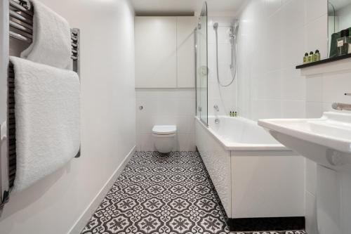 a white bathroom with a sink and a toilet at Marlin Canary Wharf in London