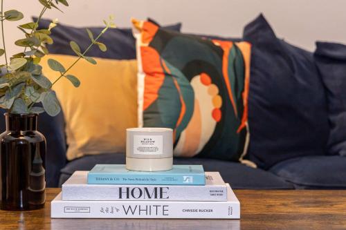 a stack of books on a table with a candle at Canal Street Apartment in Manchester