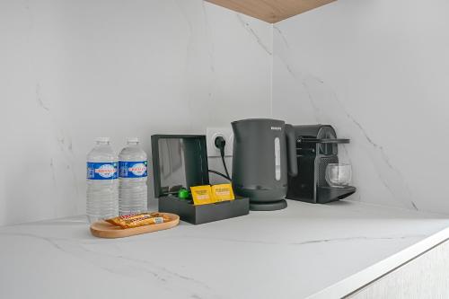 a kitchen counter with bottles of water and a coffee maker at JIJI Suites in Combs-la-Ville