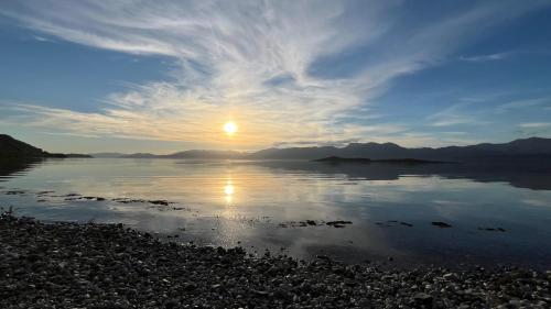 a sunset over a body of water with the sun setting at The Heronry Hideaway with luxury hot tub in Ballachulish