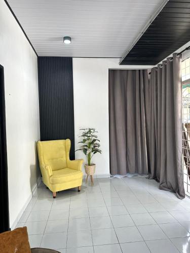 a yellow chair in a room with a curtain at Diemaz Homestay in Sungai Petani