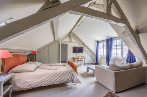 an attic bedroom with a bed and a chair at Belle maison de pêcheurs Normande refaite par un architecte in Trouville-sur-Mer