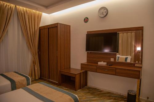 a hotel room with a bed and a desk with a mirror at شقق حديقة الروابي إين in Jeddah