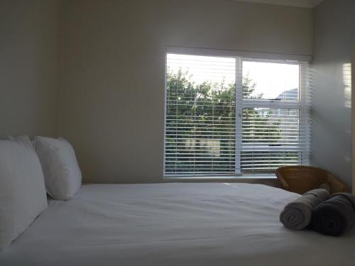 a bedroom with a white bed with a large window at Seafront! Home in Boggomsbay in Boggomsbaai
