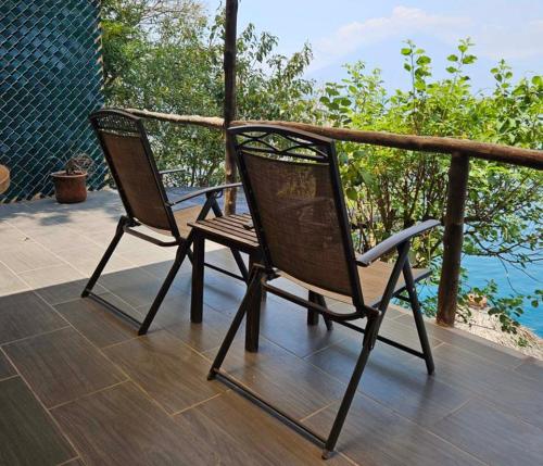 two chairs sitting on a deck near the water at Atitlan Sunset Lodge in Santa Cruz La Laguna