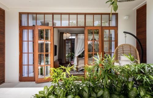 a room with glass doors and plants at Plawa Laguna Bali in Canggu
