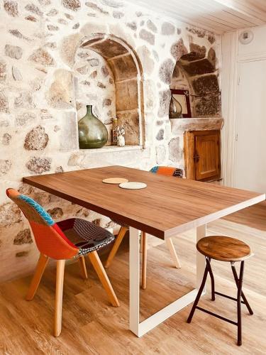 une table et des chaises dans une pièce avec un mur en pierre dans l'établissement Chez Madeleine, Entre le Lioran et Vic-sur-Cère, à Thiézac