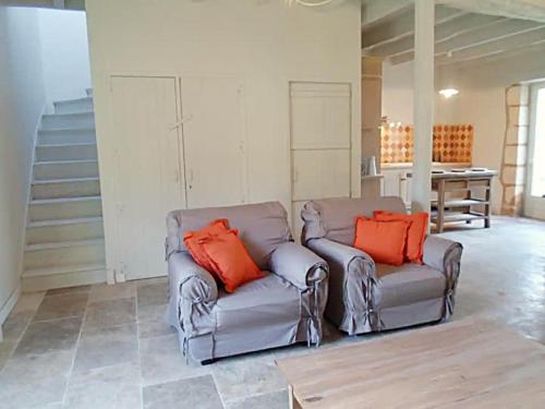 a living room with two gray couches with orange pillows at Domaine de Monciaux 2 piscines Tennis 40 Pers in Bourrou