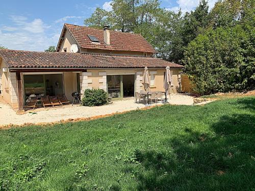 a house with a patio and a yard with chairs and umbrellas at Domaine de Monciaux 2 piscines Tennis 40 Pers in Bourrou