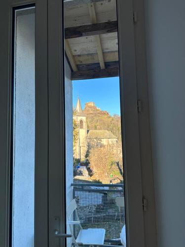 une fenêtre ouverte avec vue sur une église dans l'établissement Appartement face au château, à Murol