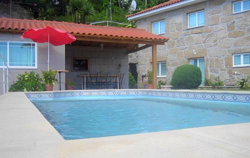 a swimming pool in front of a house with a red umbrella at Casa Tadeu in Anjos