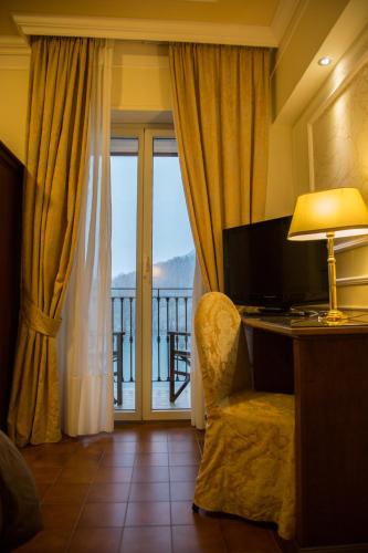 a room with a desk with a lamp and a window at Parco del Lago Resort & SPA in Villagrande