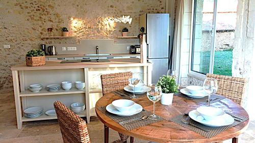 a kitchen with a wooden table with chairs and a tableablish at Domaine de Monciaux 2 piscines Tennis 40 Pers in Bourrou
