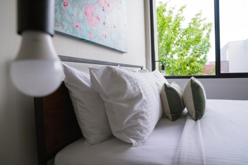 a group of pillows on a bed with a window at Spacious Richmond Home - Walk to MCG, Venues & CBD in Melbourne