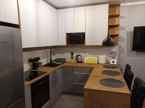a kitchen with white cabinets and a wooden counter top at Domek nad potokiem in Tylicz