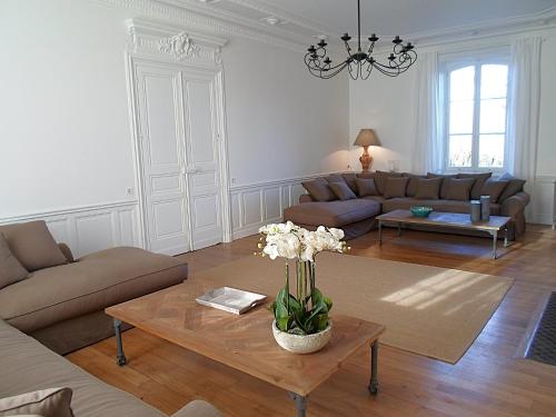 a living room with a couch and a table with flowers at Domaine de Monciaux 2 piscines Tennis 40 Pers in Bourrou