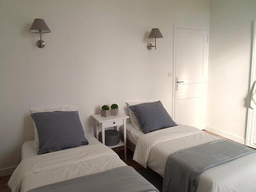 a bedroom with two beds and a table with a night stand at Domaine de Monciaux 2 piscines Tennis 40 Pers in Bourrou