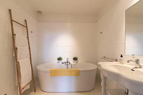 a white bathroom with a tub and two sinks at Domaine de Monciaux 2 piscines Tennis 40 Pers in Bourrou