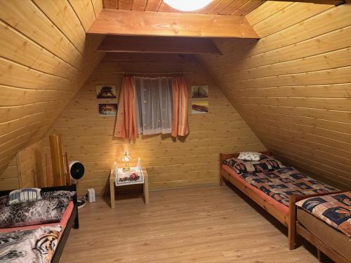 a attic room with two beds and a window at Na samotě u lesa in Vsetín