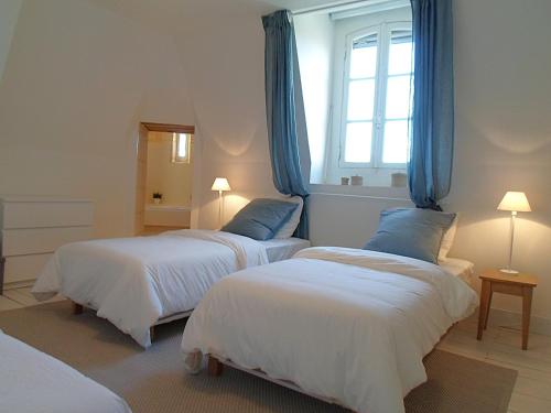 a bedroom with two beds with blue curtains and a window at Domaine de Monciaux 2 piscines Tennis 40 Pers in Bourrou