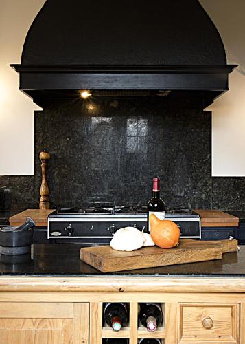 a kitchen with a stove and a bottle of wine at Domaine de Monciaux 2 piscines Tennis 40 Pers in Bourrou