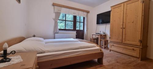a bedroom with a large bed and a television at Apartments Pod macesnovo streho in Solčava