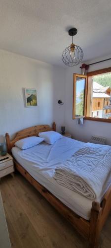 - une chambre dotée d'un grand lit avec des draps bleus et une fenêtre dans l'établissement Les Orres 1800 vue montagne 4 à 6 couchages avec parking, aux Orres