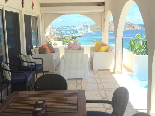 a patio with white chairs and a view of the ocean at Well maintained and makes you feel right at home in Oyster Pond