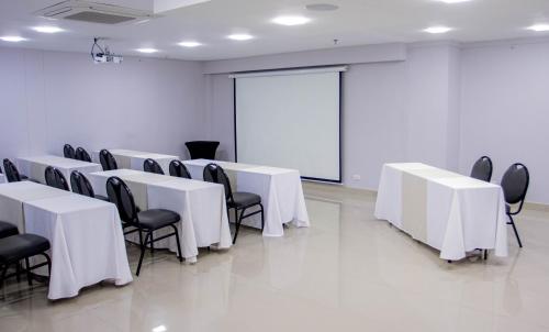 a conference room with white tables and chairs and a white screen at Hotel Soratama in Pereira