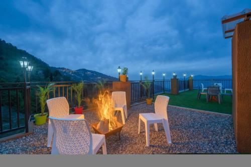 a fire pit on a patio with chairs and a table at The Sky Mountain Kufri I Serviced Villa I Balcony I Valley and Mountain View I Family Groups & Bonfire I Memories & Enjoyment Villa I Operated Charvi Retreat by Exotic Stays in Kūfrī