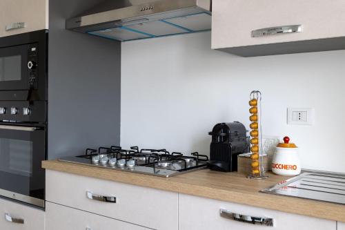 a kitchen with a stove top oven next to a microwave at Arya's Corner by the Lake - Parcheggio - Vista lago in Arona