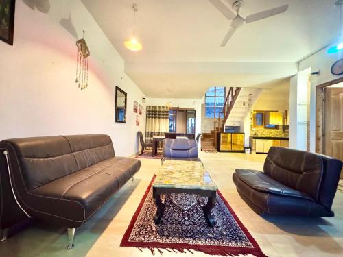 a living room with a leather couch and a table at The Sky Mountain Kufri I Serviced Villa I Balcony I Valley and Mountain View I Family Groups & Bonfire I Memories & Enjoyment Villa I Operated Charvi Retreat by Exotic Stays in Kūfrī