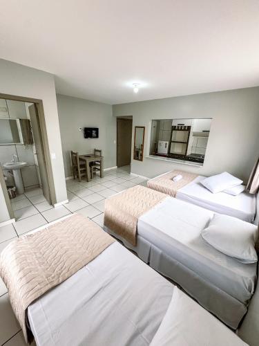 a hotel room with three beds and a bathroom at Hotel Zata - Premium in Criciúma