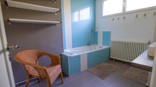 La salle de bains est pourvue d'une baignoire, d'une chaise et d'un lavabo. dans l'établissement Mas - 12 pers - Piscine - Grand Jardin Arboré, à Ruoms