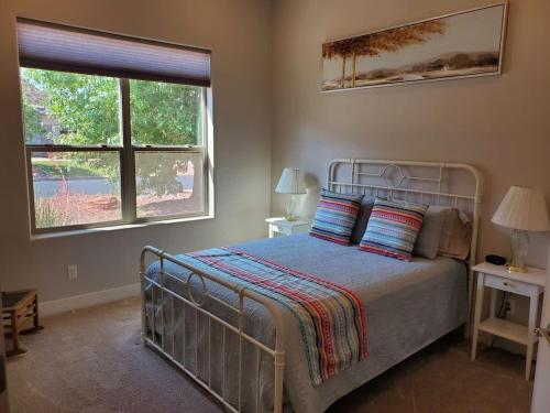 a bedroom with a bed and two windows at Coral Cliff View - Amazing Views and Pool in Kanab