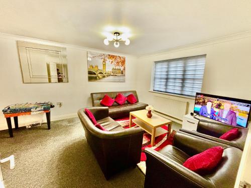 a living room with leather furniture and a flat screen tv at Conveniently located 3 bed spacious home for couples, families and groups in Ipswich in Ipswich