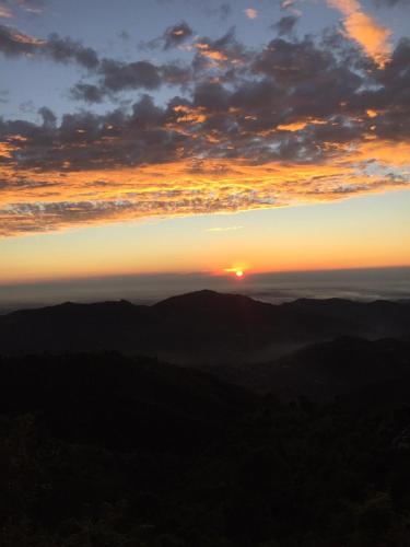a view of the sunset from the top of a mountain at The Sky Mountain Kufri I Serviced Villa I Balcony I Valley and Mountain View I Family Groups & Bonfire I Memories & Enjoyment Villa I Operated Charvi Retreat by Exotic Stays in Kūfrī
