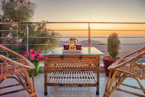 a table with a tea kettle on a balcony with two chairs at The Sky Mountain Kufri I Serviced Villa I Balcony I Valley and Mountain View I Family Groups & Bonfire I Memories & Enjoyment Villa I Operated Charvi Retreat by Exotic Stays in Kūfrī